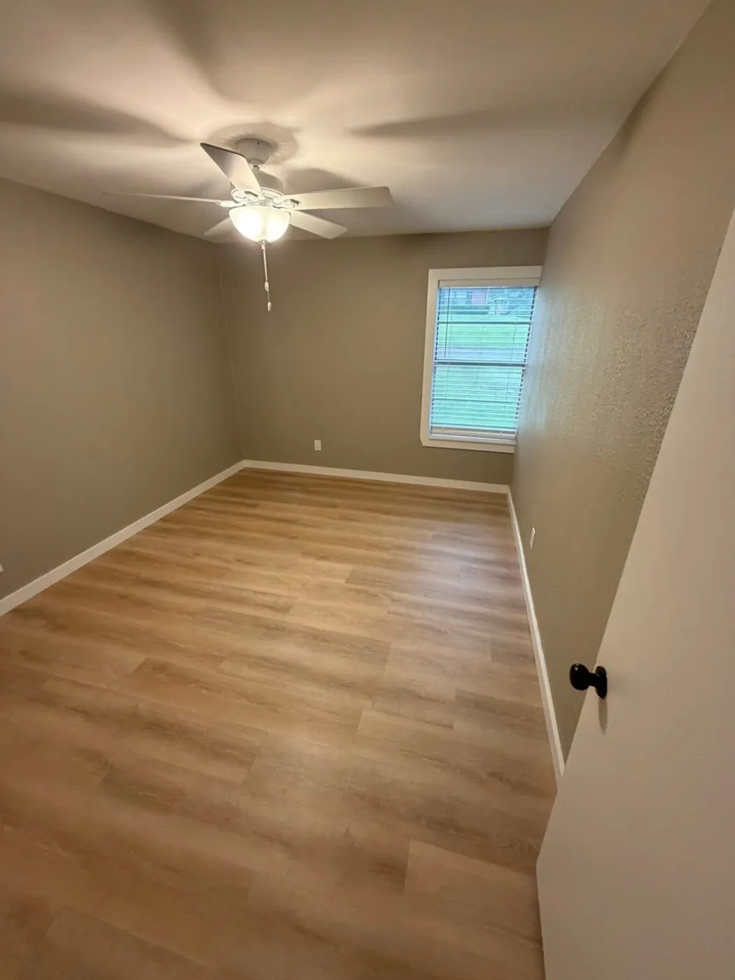 Bedroom with new flooring, paint, and ceiling fan