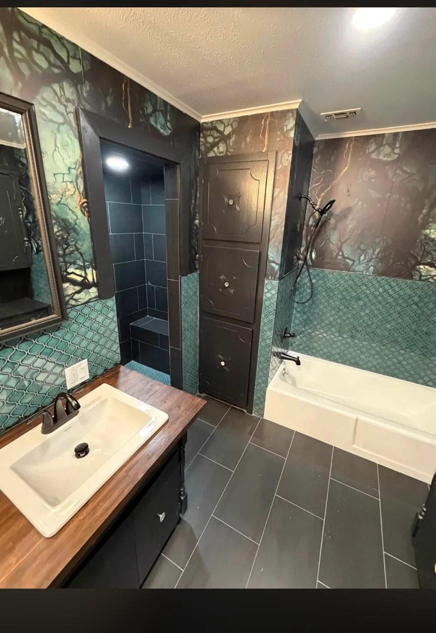 Finished master bathroom with dark tile floor, teal accents, and white soaking tub
