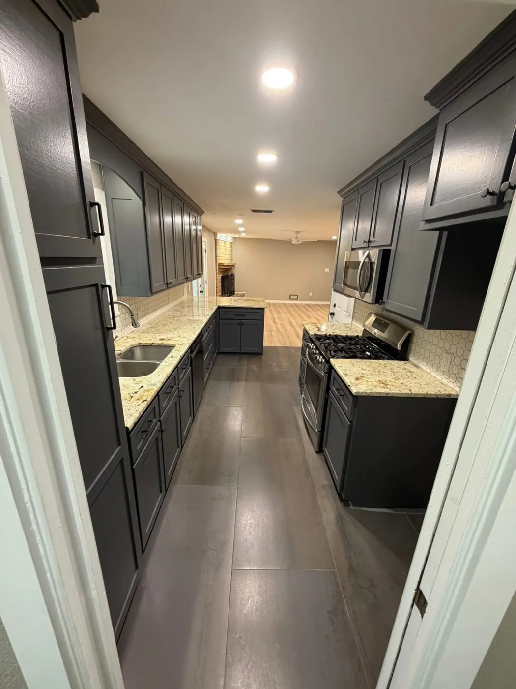 Galley kitchen with dark cabinets, hexagon tile backsplash, and gas range