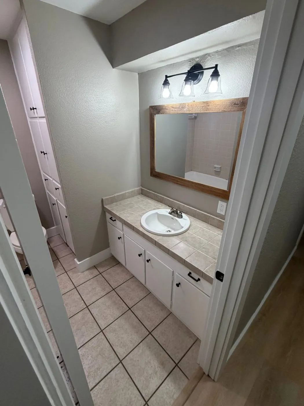 Hall bathroom with refreshed vanity, new light fixture, and framed mirror