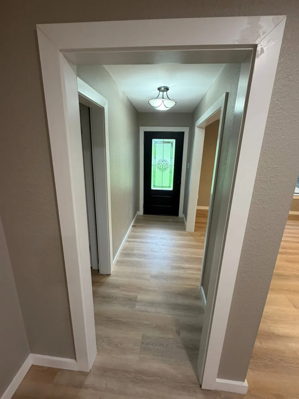 Entry hallway with fresh paint, white trim, and new flooring